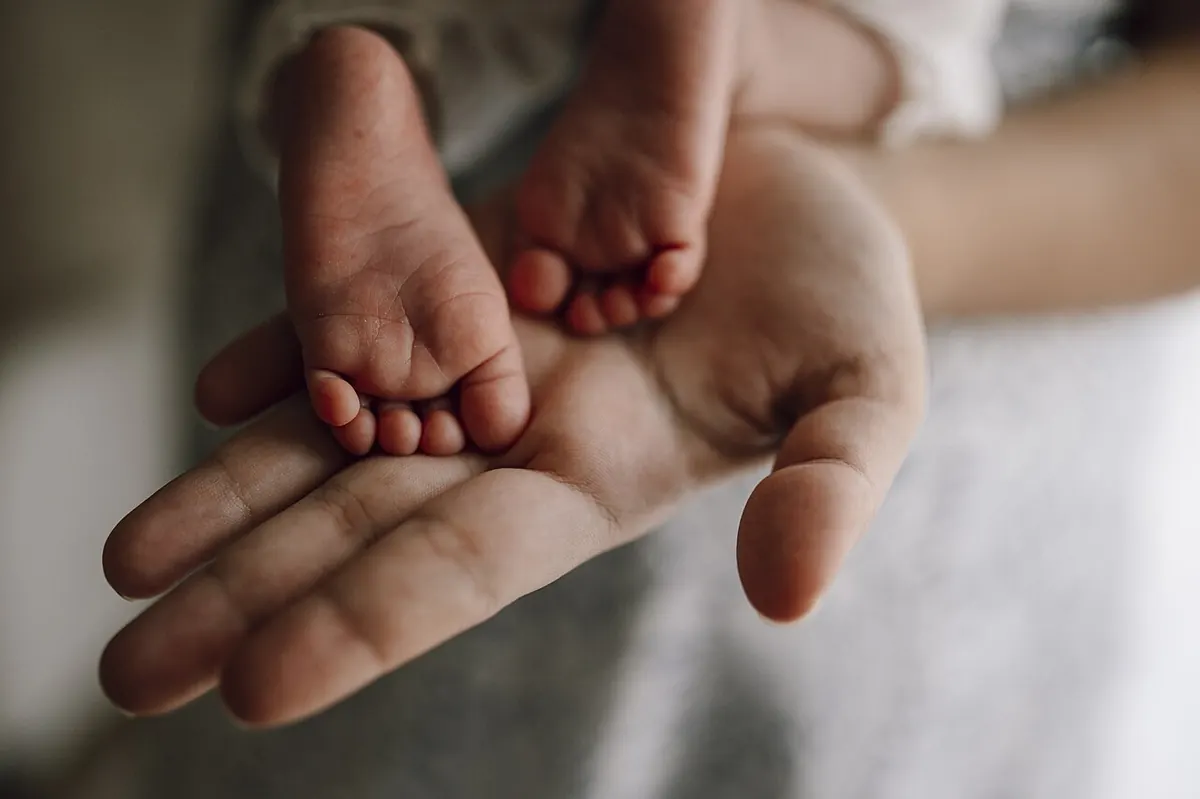 Крачетата на новородено в дланта на родител